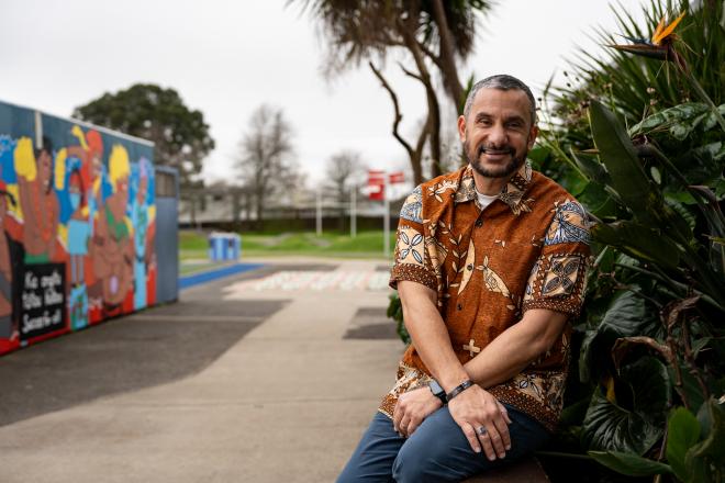 Aspiring Principal Programme mentor Banapa is sitting outside the school building in front of a garden.