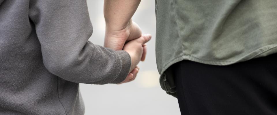 a closeup of a student and a teacher holding hands