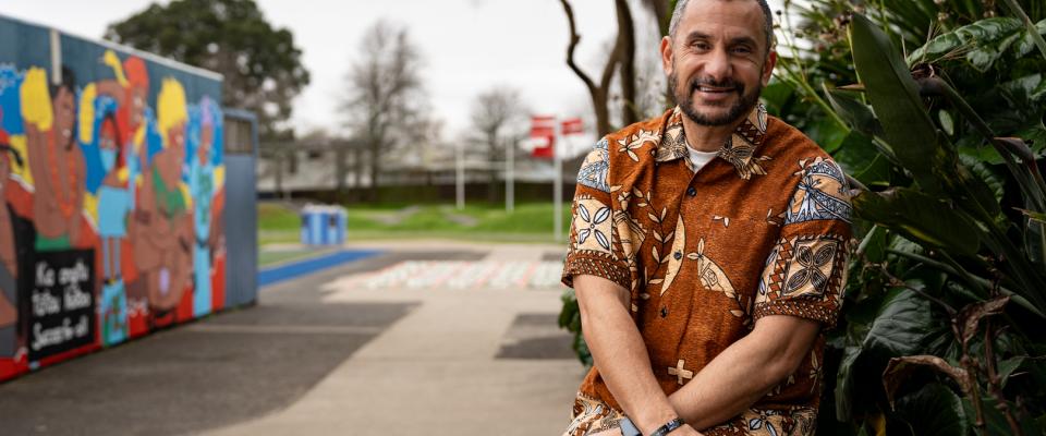 Aspiring Principal Programme mentor Banapa is sitting outside the school building in front of a garden.